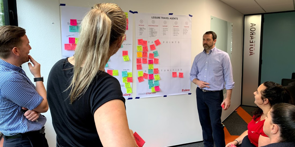 Adam discussing stages of a journey map with clients during a workshop